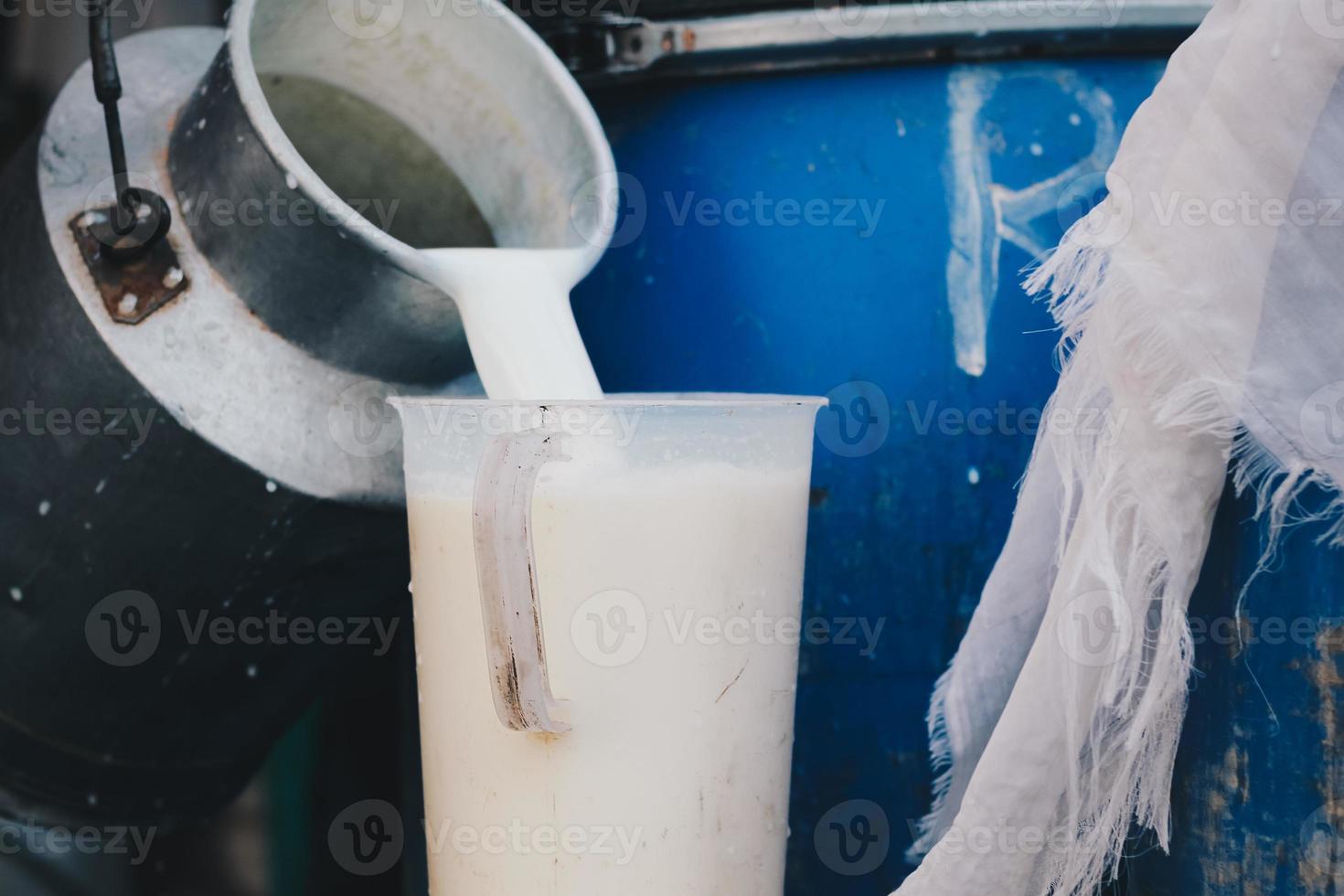 agricultor vertiendo leche cruda de la granja lechera en un recipiente para venderla a industrias o mercados foto