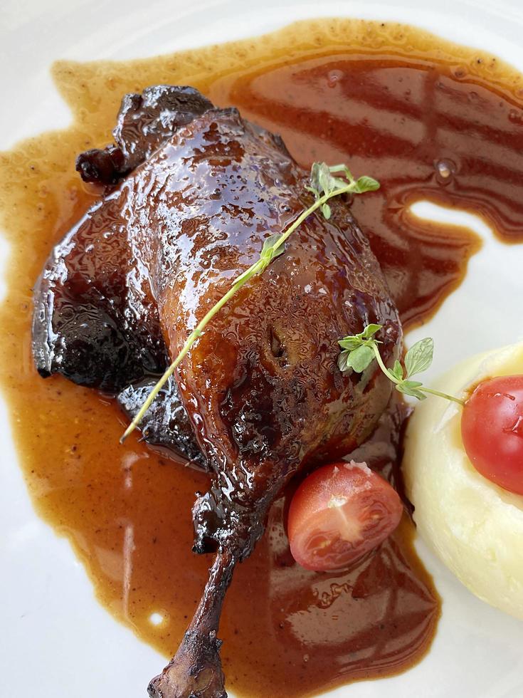Duck leg in pear confit close-up photo
