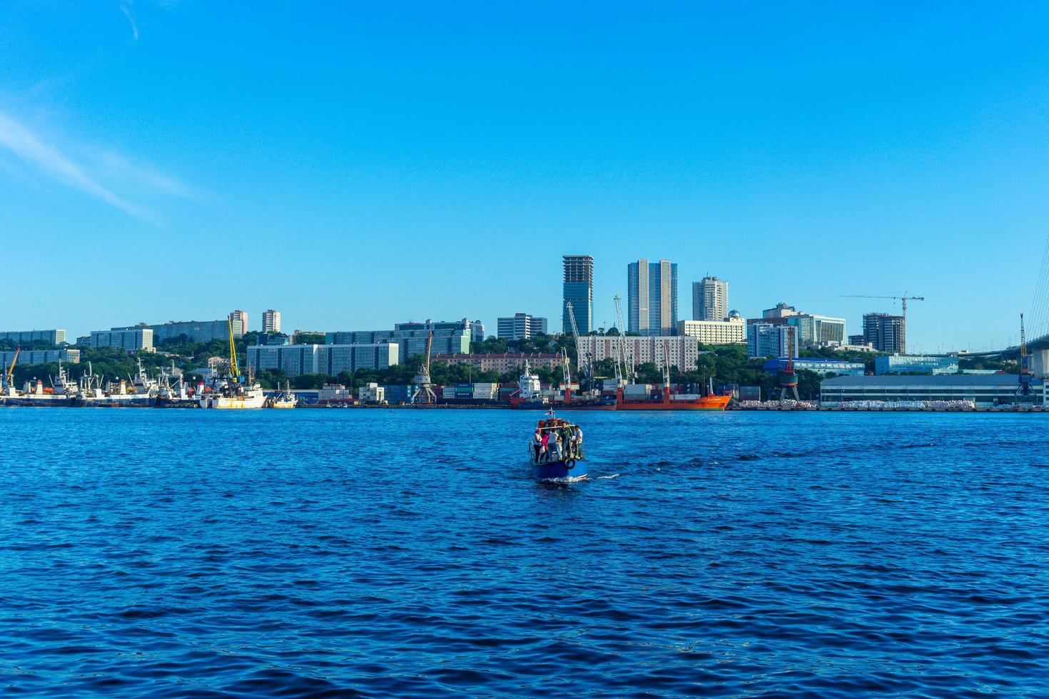 Vladivostok, Russia - August 11, 2018-Cityscape with a small boat on the background of the sea. photo