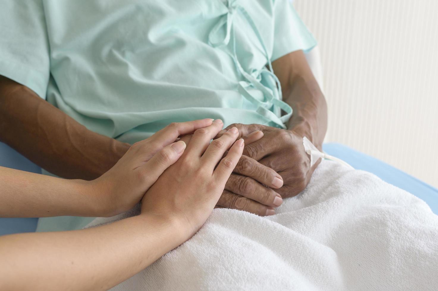 Close up of visitor holding senior patient's hand in hospital, health care and medical concept photo