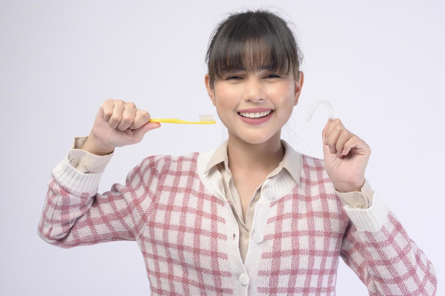 Young smiling woman holding invisalign braces over white background studio, dental healthcare and Orthodontic concept. photo