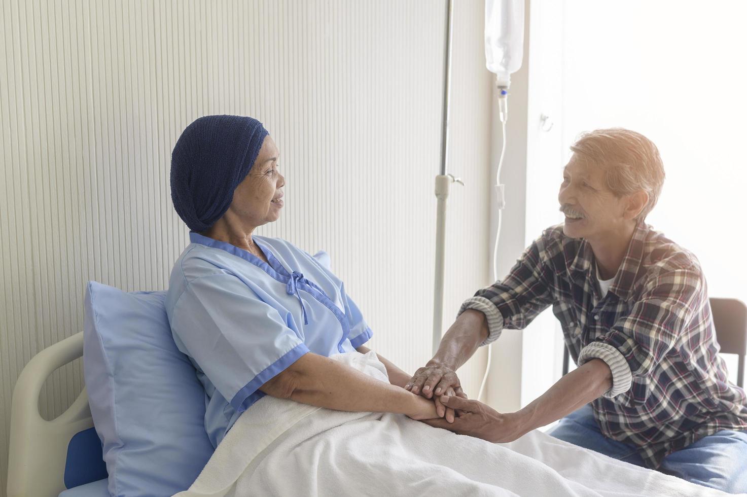 Senior man visiting cancer patient woman wearing head scarf at hospital, health care and medical concept photo