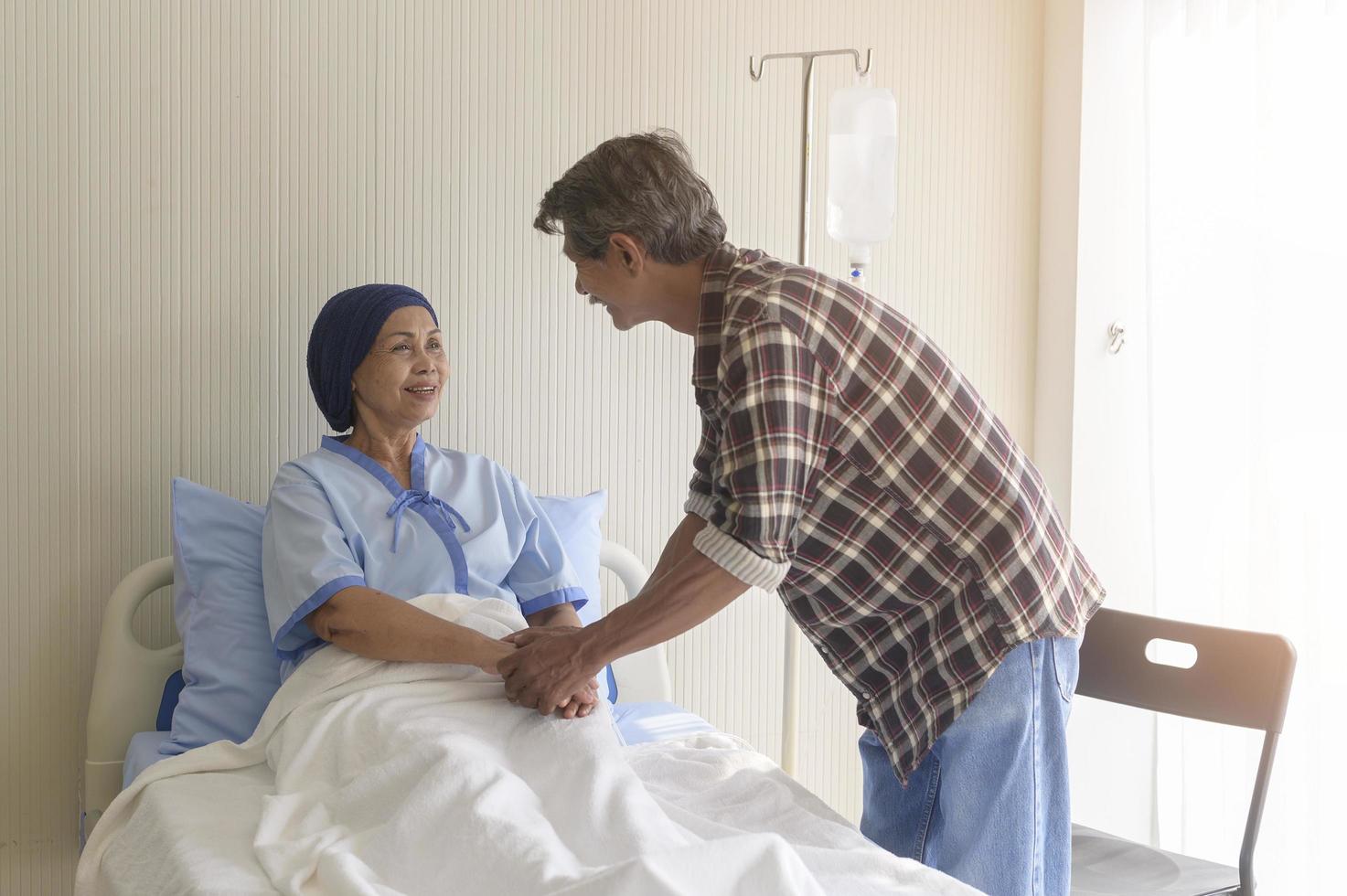Senior man visiting cancer patient woman wearing head scarf at hospital, health care and medical concept photo