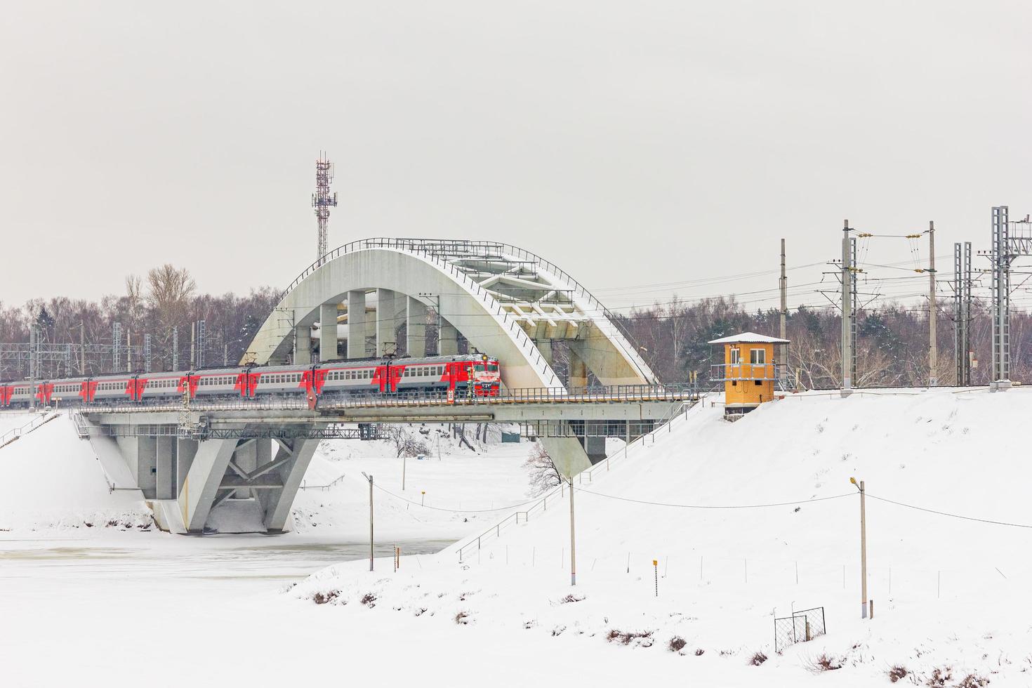 A frozen river with a bridge and a moving train photo