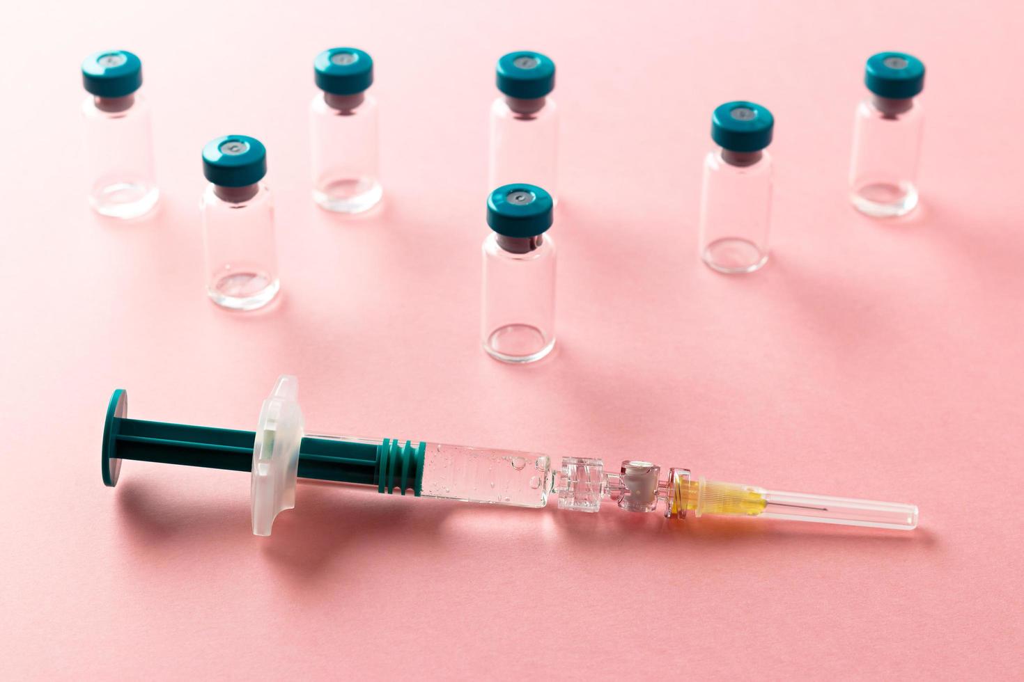 Syringe with several medical vials for injecting on pink background. photo