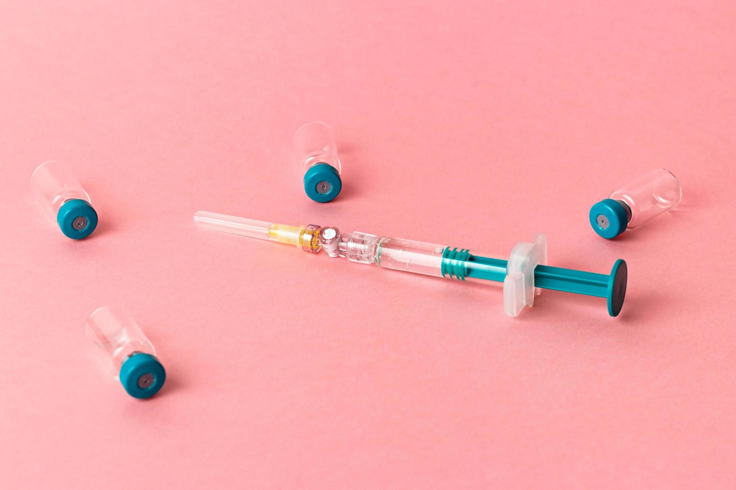 Syringe with several medical vials for injecting on pink background. photo