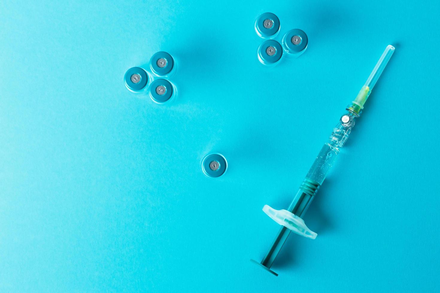 Syringe with several medical vials for injection on blue background. Top view. photo