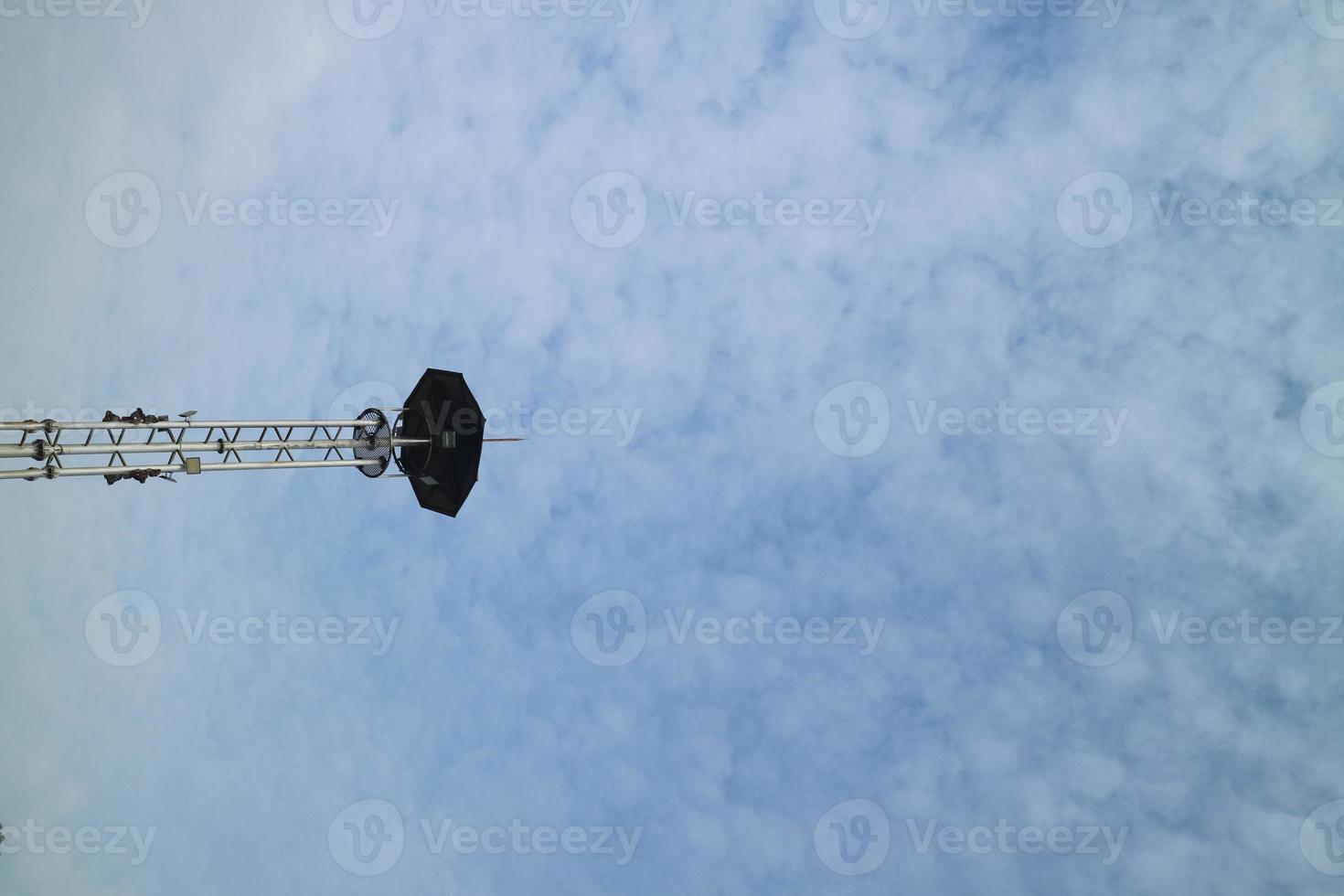 a high lamppost under a bright cloud photo