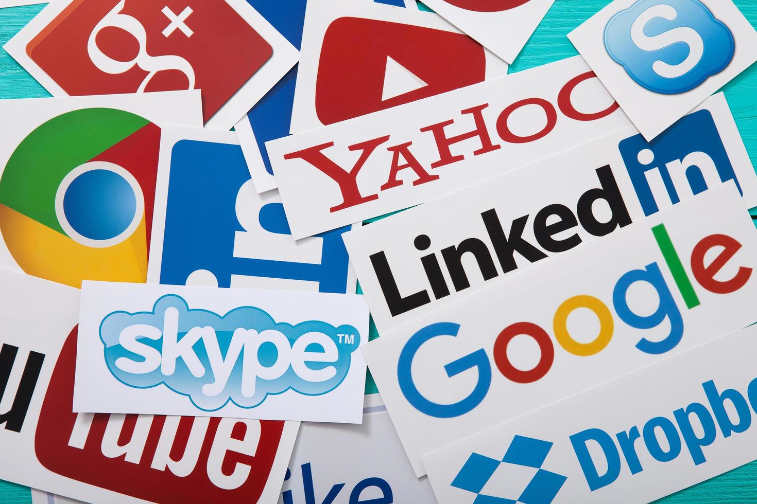 KIEV, UKRAINE - MARCH 10, 2017. Collection of popular social media logos printed on paper YouTube,Facebook, Twitter, Google Plus, Yahoo, Linkedin, Snapchat, Chrome and like on blue wooden background. photo