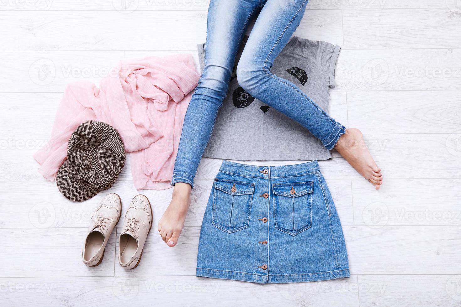 Teenager outfit with different accessories and female legs in jeans on white wooden floor. Top view and copy space. photo