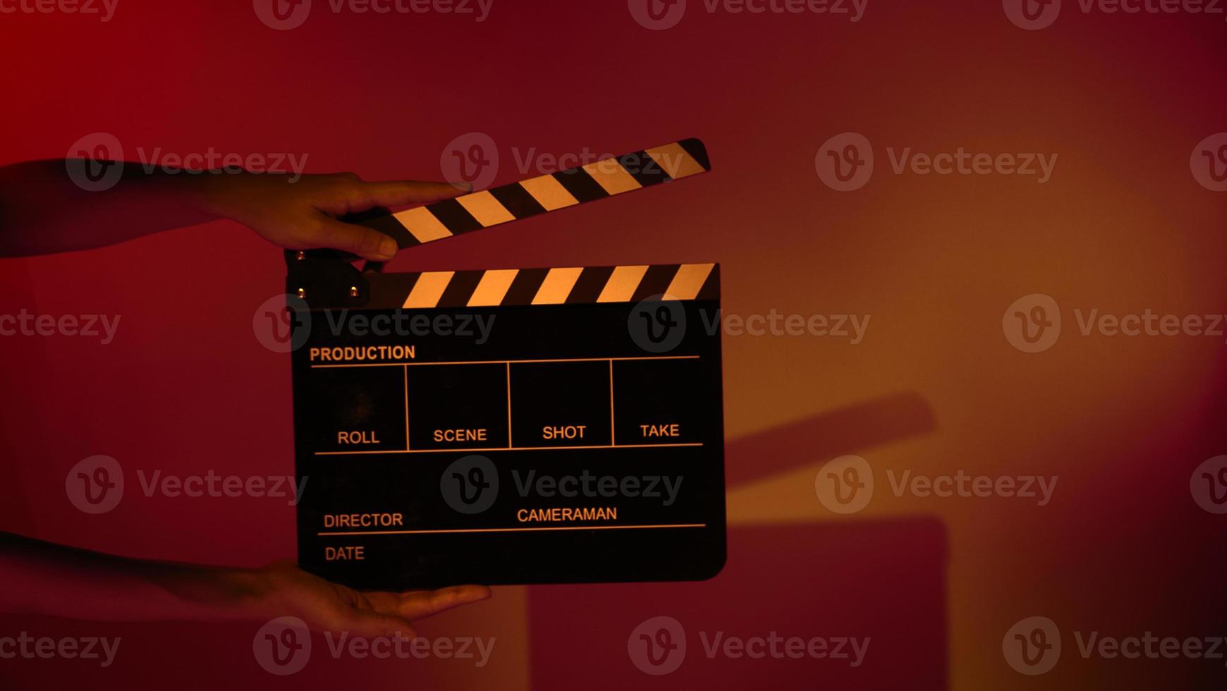 Hand holds empty film making clapperboard on color background in studio photo