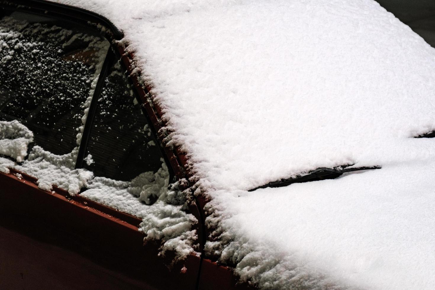 close up of snow-covered windshield of a car after snowfall outside photo