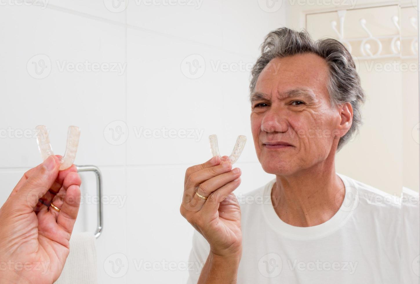 Man Putting in his Night Guard in Front of a Mirror photo