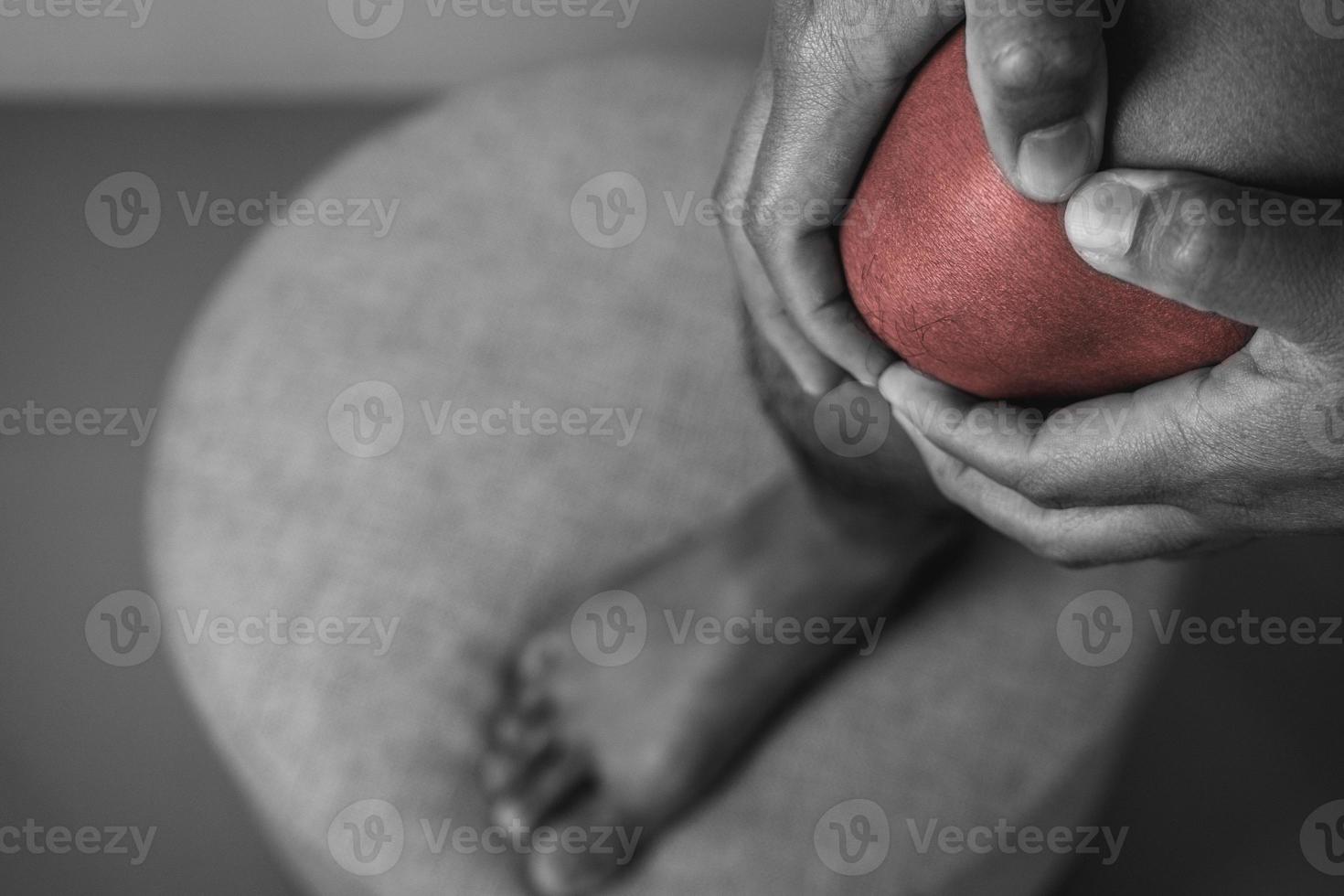 The man holds his pain point of knee joint. The red point shows position of Injury. Black and white color. photo