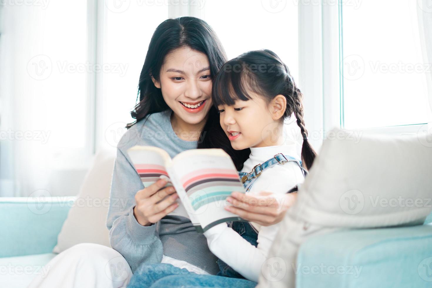 image of mother and daughter sitting on the sofa reading a book photo