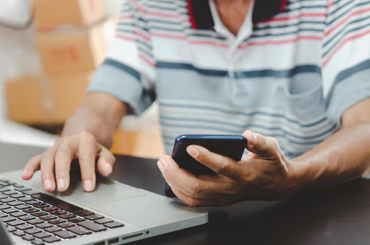 man hand using smart phone and laptop on table at home, searching information browsing the internet on web, work from home.Business shopping online concept photo