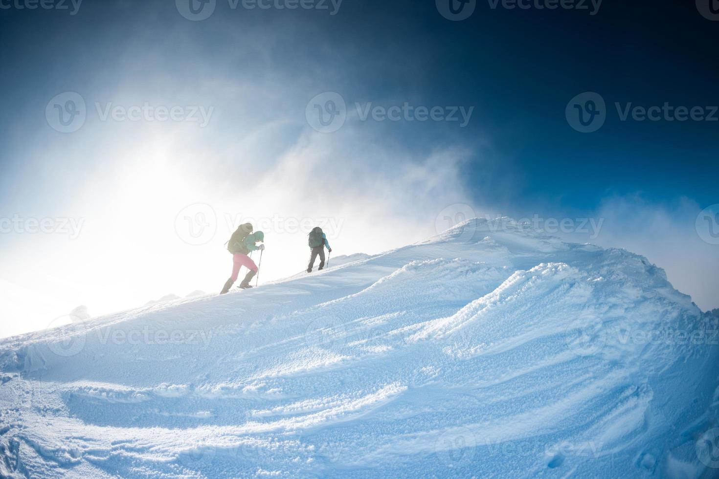 climbers climb to the top of the mountain in winter photo