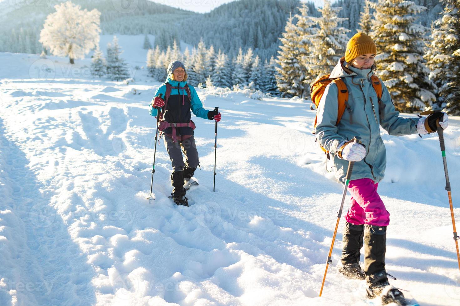 dos mujeres caminan con raquetas de nieve en el trekking de invierno foto