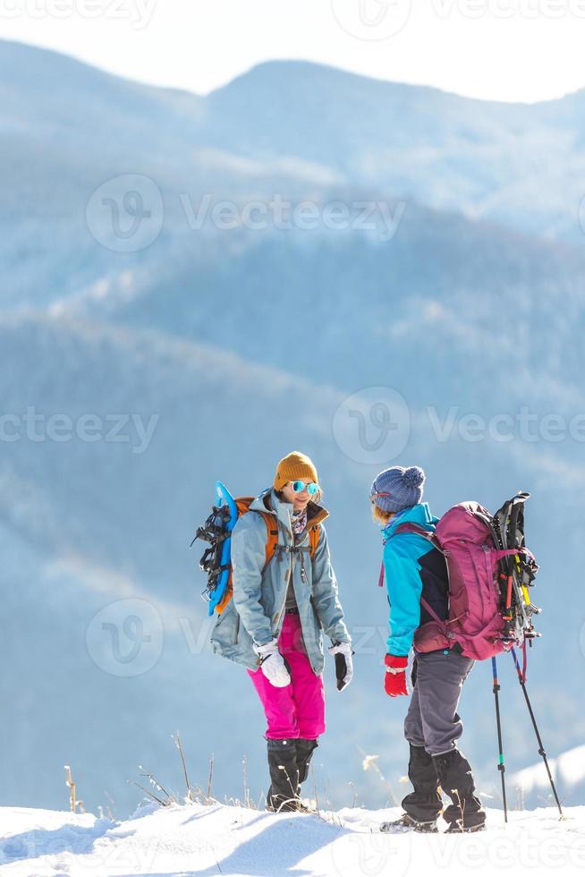 two women climbed to the top of the mountain during a winter hike photo