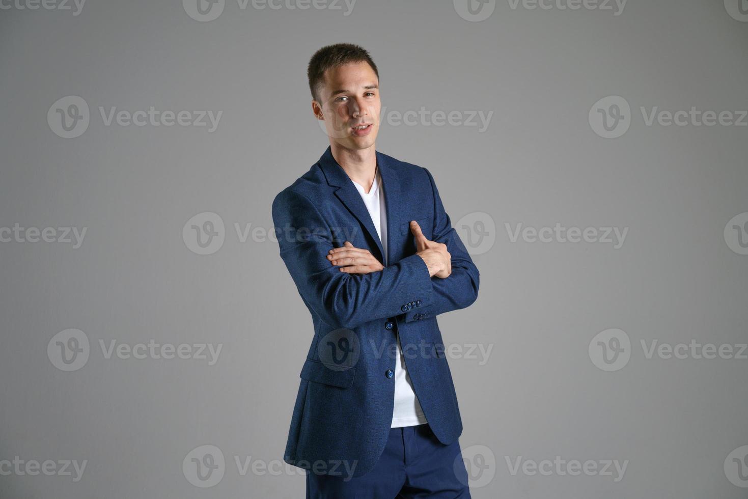 A young businessman in a blue jacket on a gray background photo