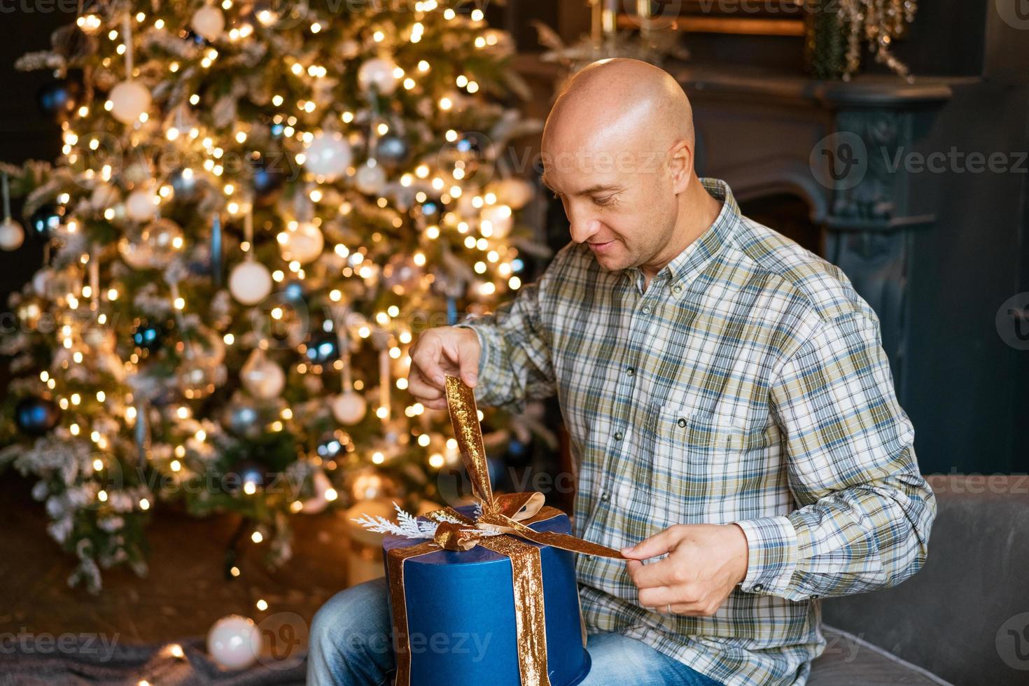 hombre calvo feliz abre un regalo de navidad foto