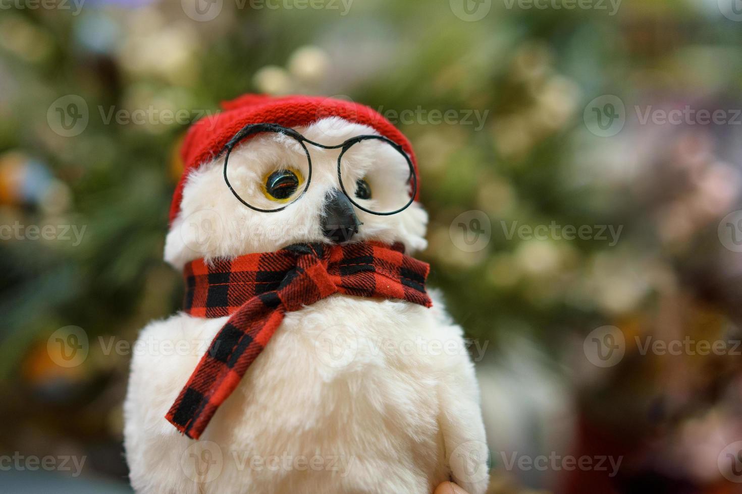 búho de juguete con gafas y bufanda en el fondo del árbol de navidad foto