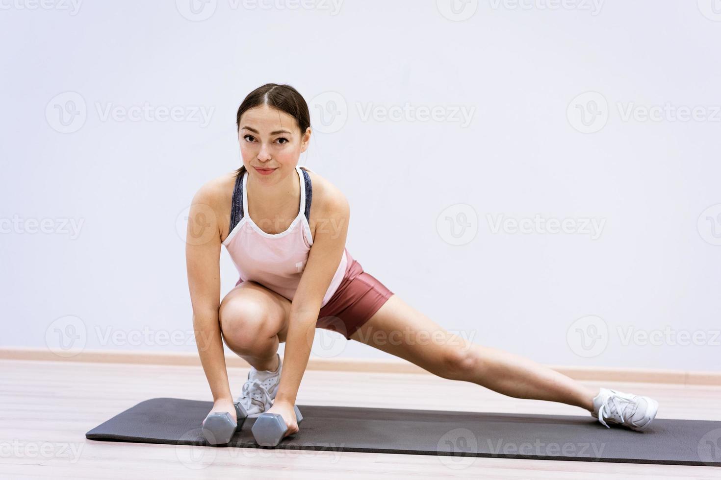 Woman doing fitness at home against wall background photo