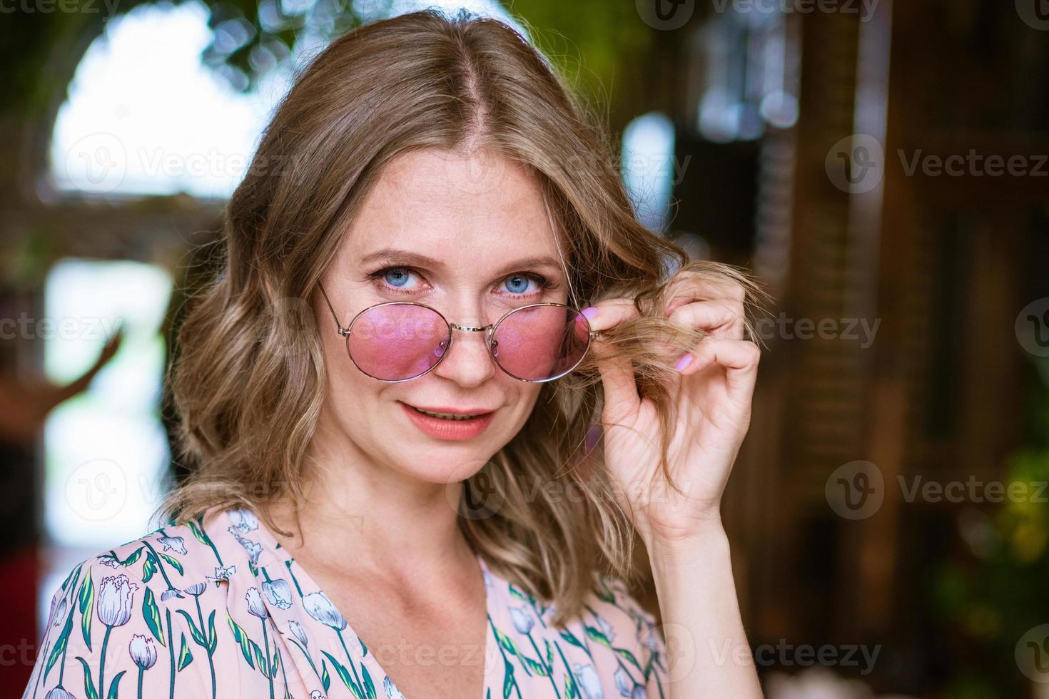 Fashionable woman in trendy pink frame glasses posing outdoors. Cute caucasian photo