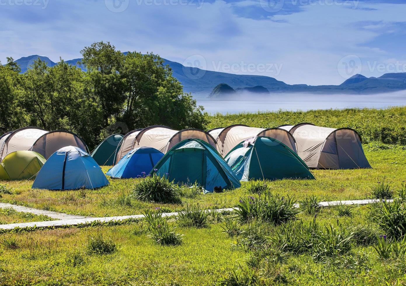 Tourists camped in the woods on the shore of the lake on the hillside. photo