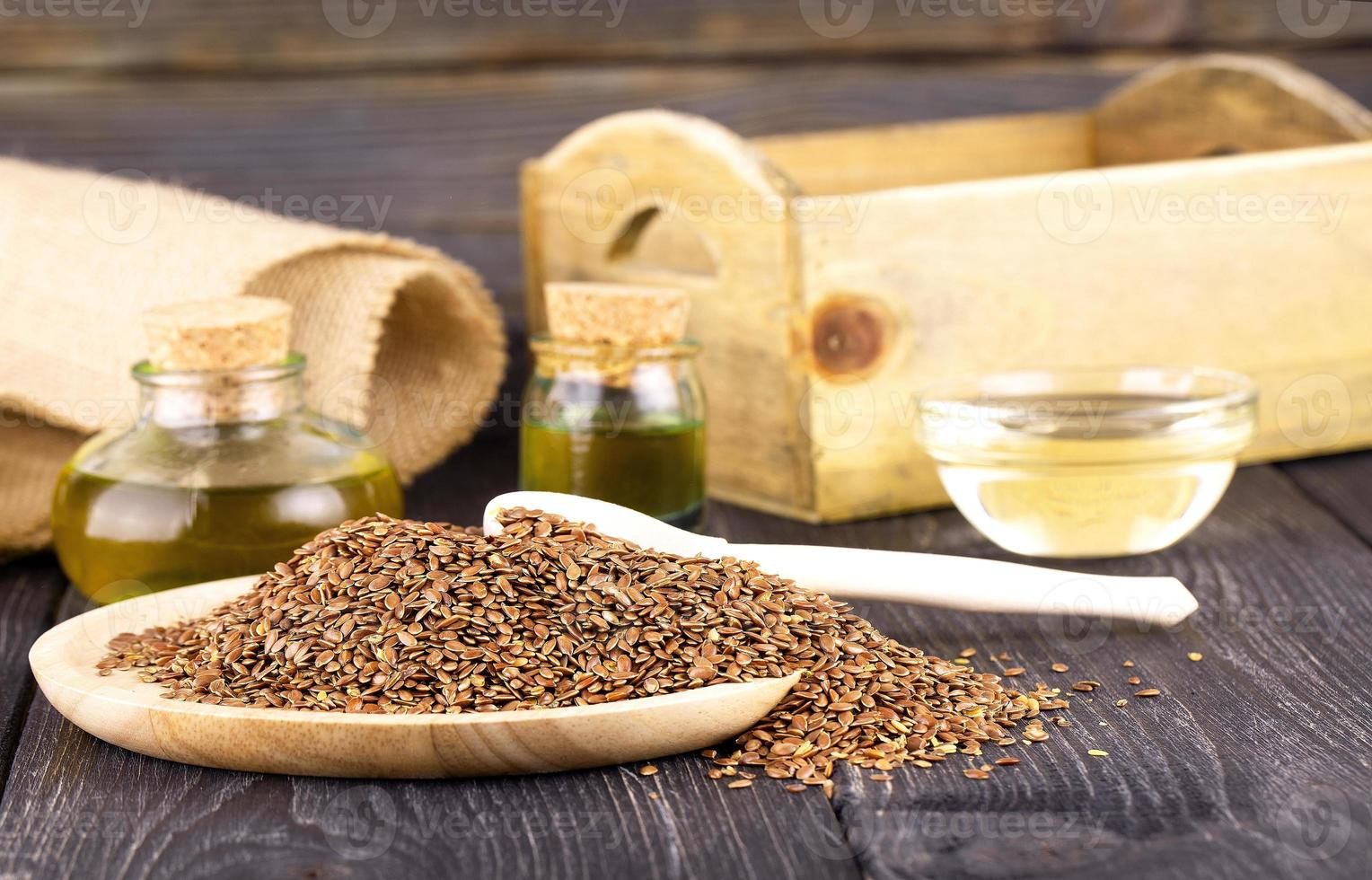 The Sesame oil in glass and seeds on wooden background photo