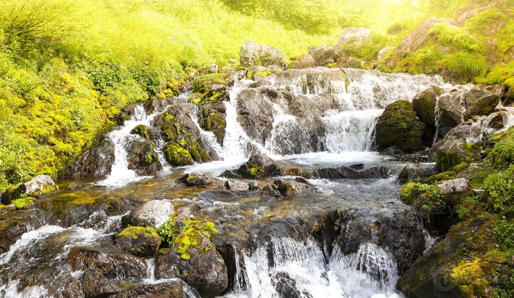 The river stream flowing over rock formations in the mountains photo