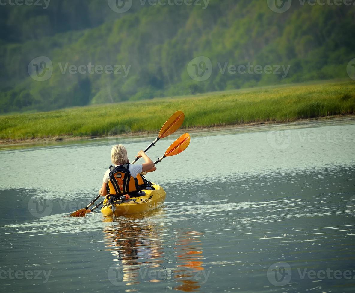 la mujer con un niño en el lago y paseo en kayak foto