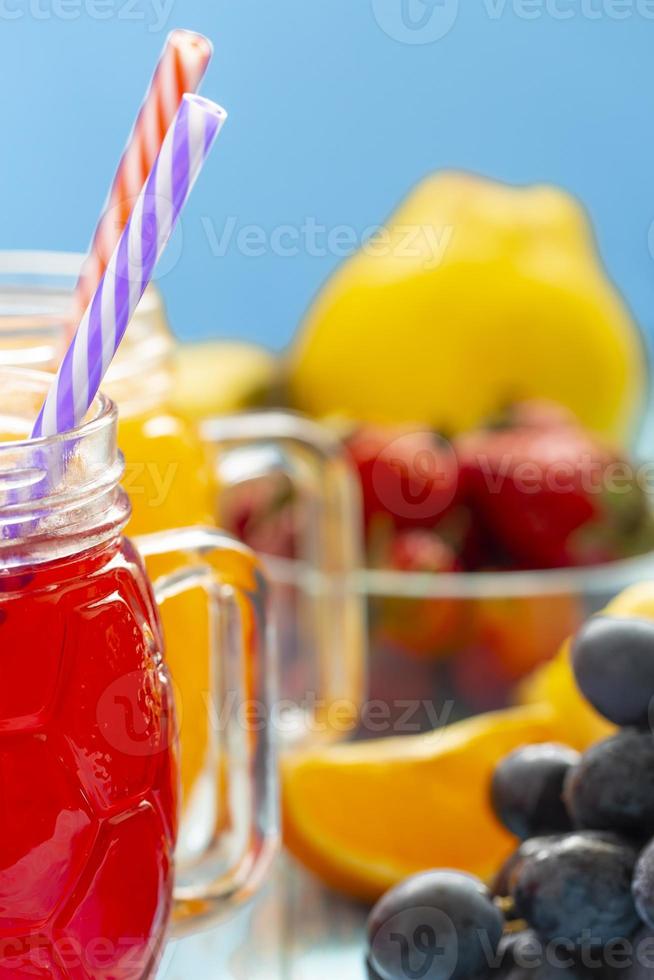 The two cups with orange juice and strawberries on blue background photo