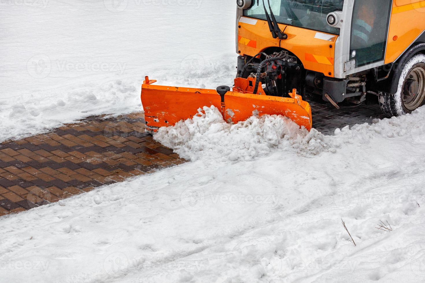 Road compact cleaner cleans snow on the sidewalk. photo