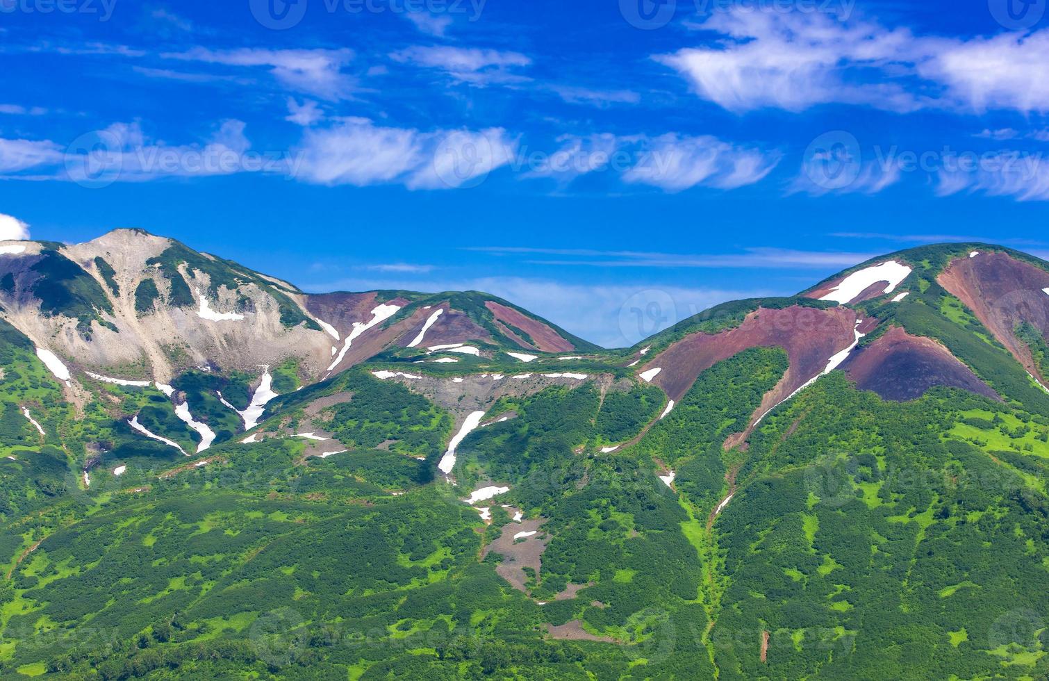 The green snowy hills on a blue sky background photo