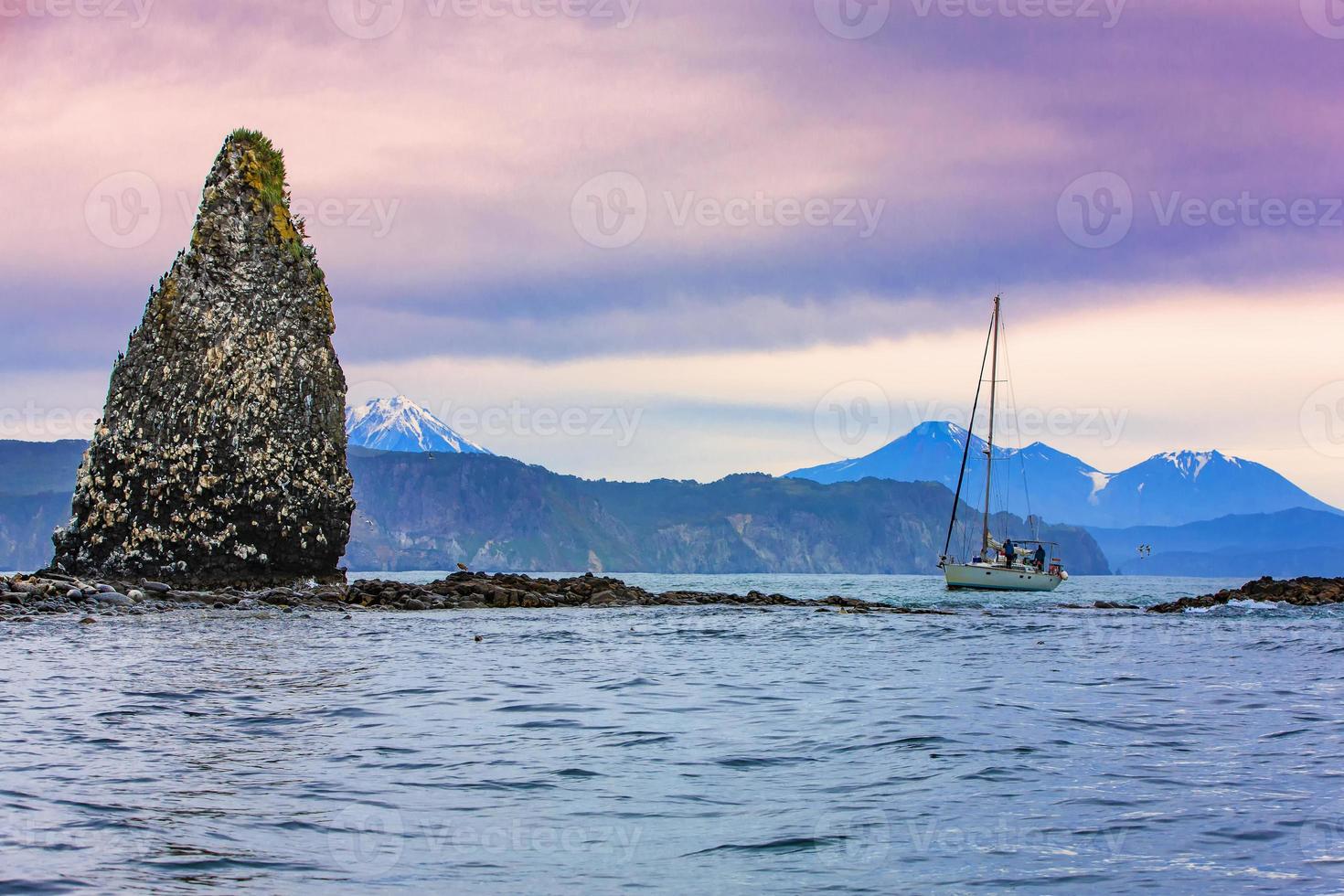 The yacht near the cliffs with nests of sea gulls in the Pacific ocean photo