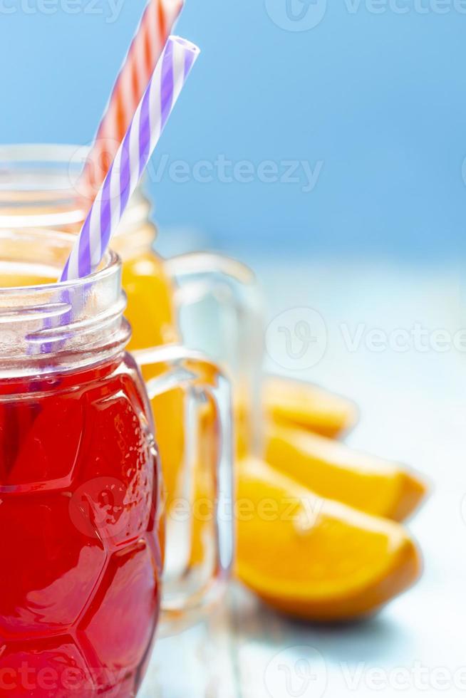The two cups with orange juice and strawberries on blue background photo