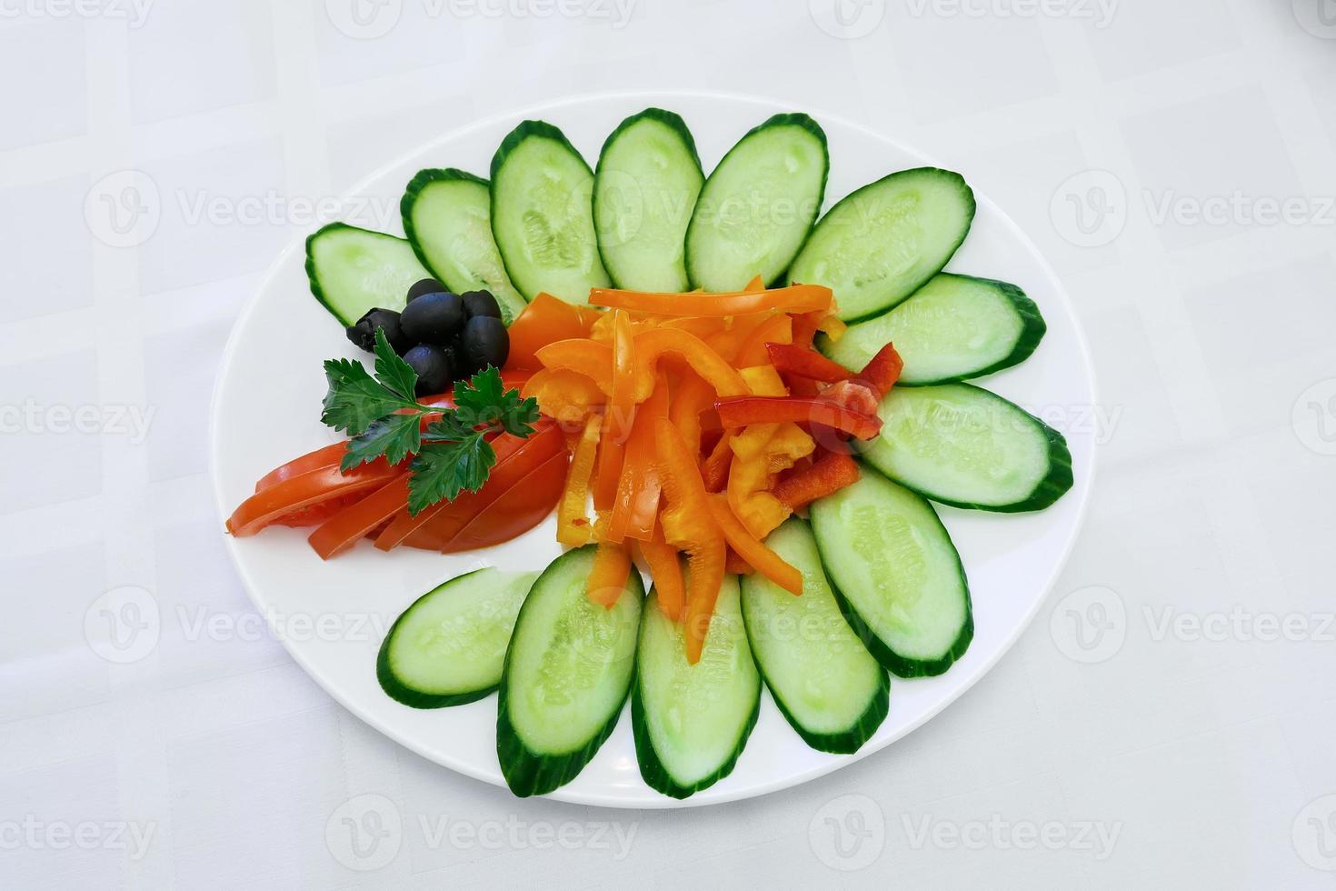 Green salad and fresh cucumbers in a bowl. Table setting photo