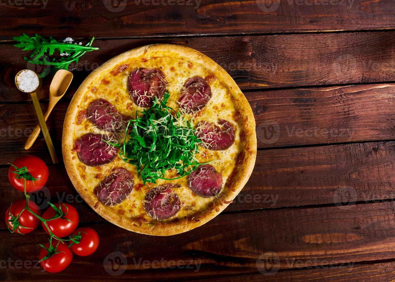 pizza con ternera en una mesa de madera. hermoso fondo foto