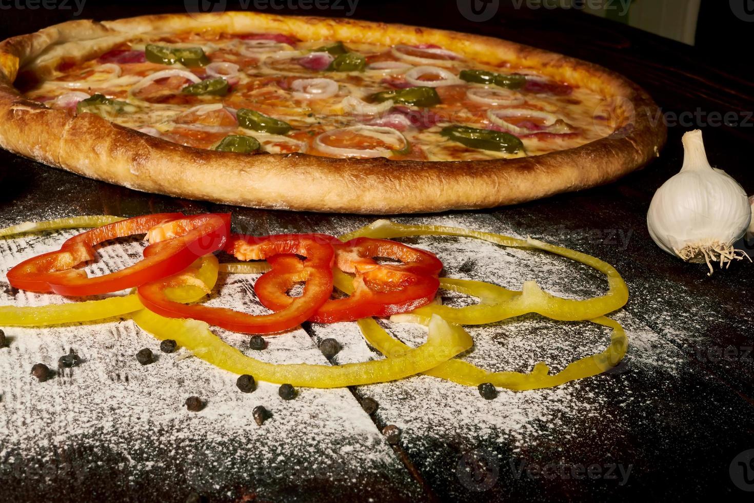 Pepperoni pizza with ham and jalapeno chili peppers on old wooden table photo