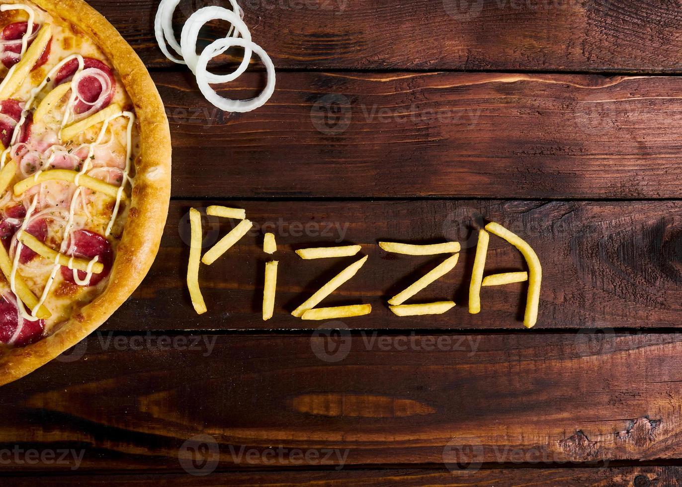 delicious Italian pizza with French fries on a wooden table photo