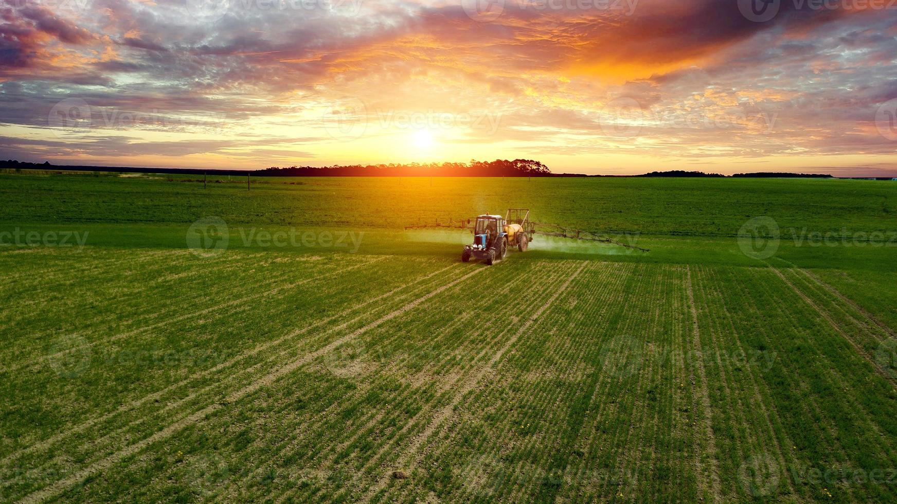 farmer working in the field on a tractor until sunset photo