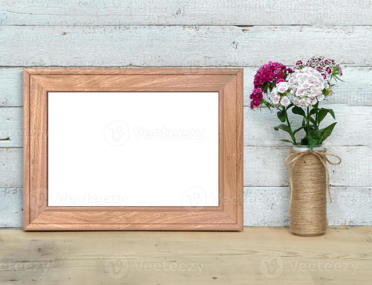 Old Wooden horizontal A4 Frame mockup near a bouquet of sweet-william stands on a wooden table on a painted white wooden background. Rustic style, simple beauty. 3d render. photo