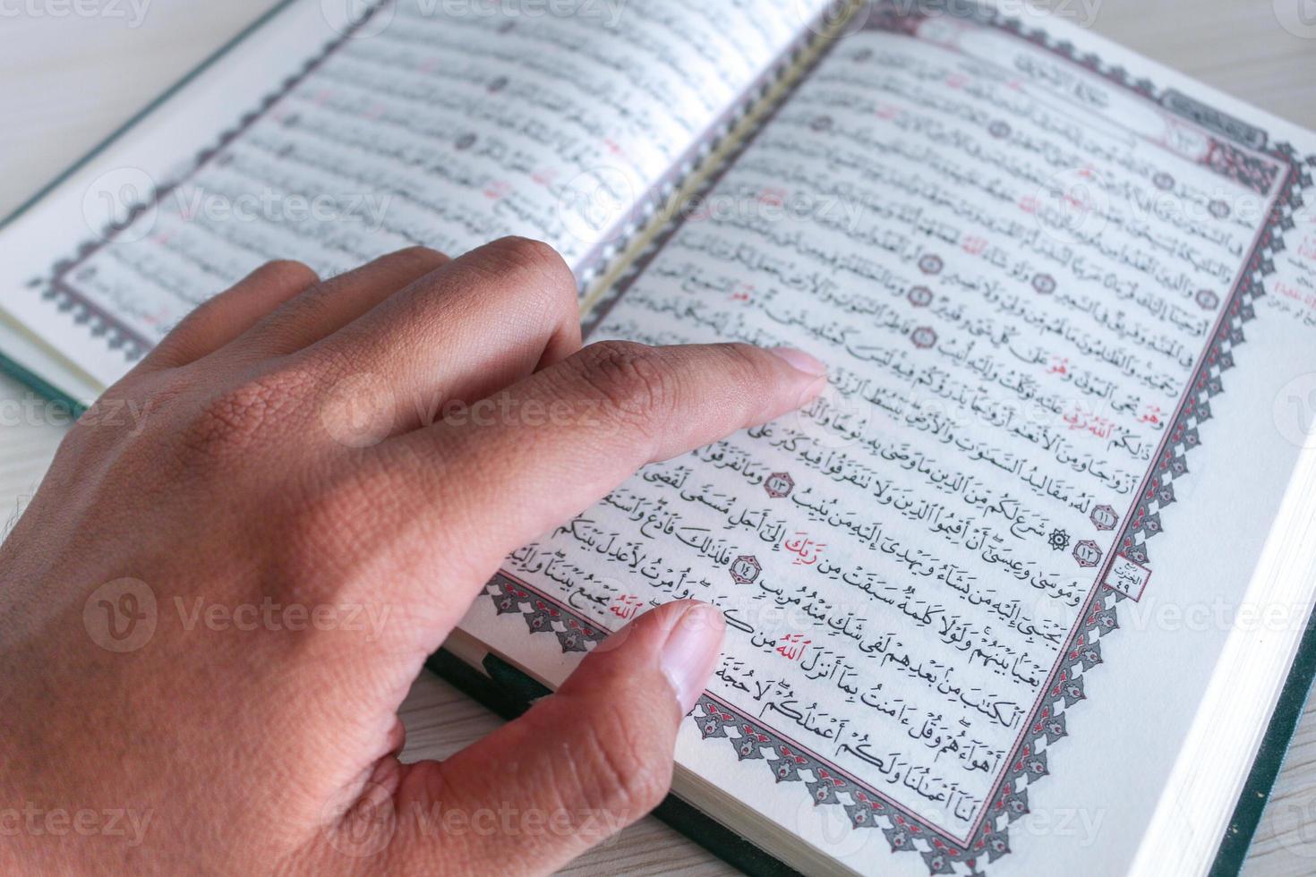 Close up of hand when reading the Holy Quran at the mosque. Selective focus photo