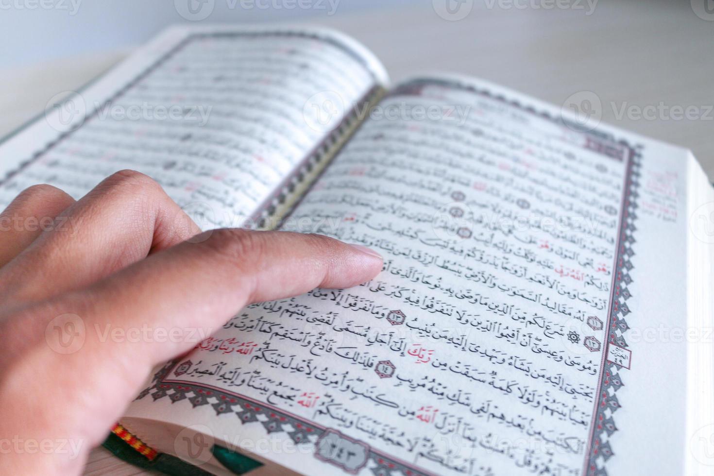 Close up of hand when reading the Holy Quran at the mosque. Selective focus photo