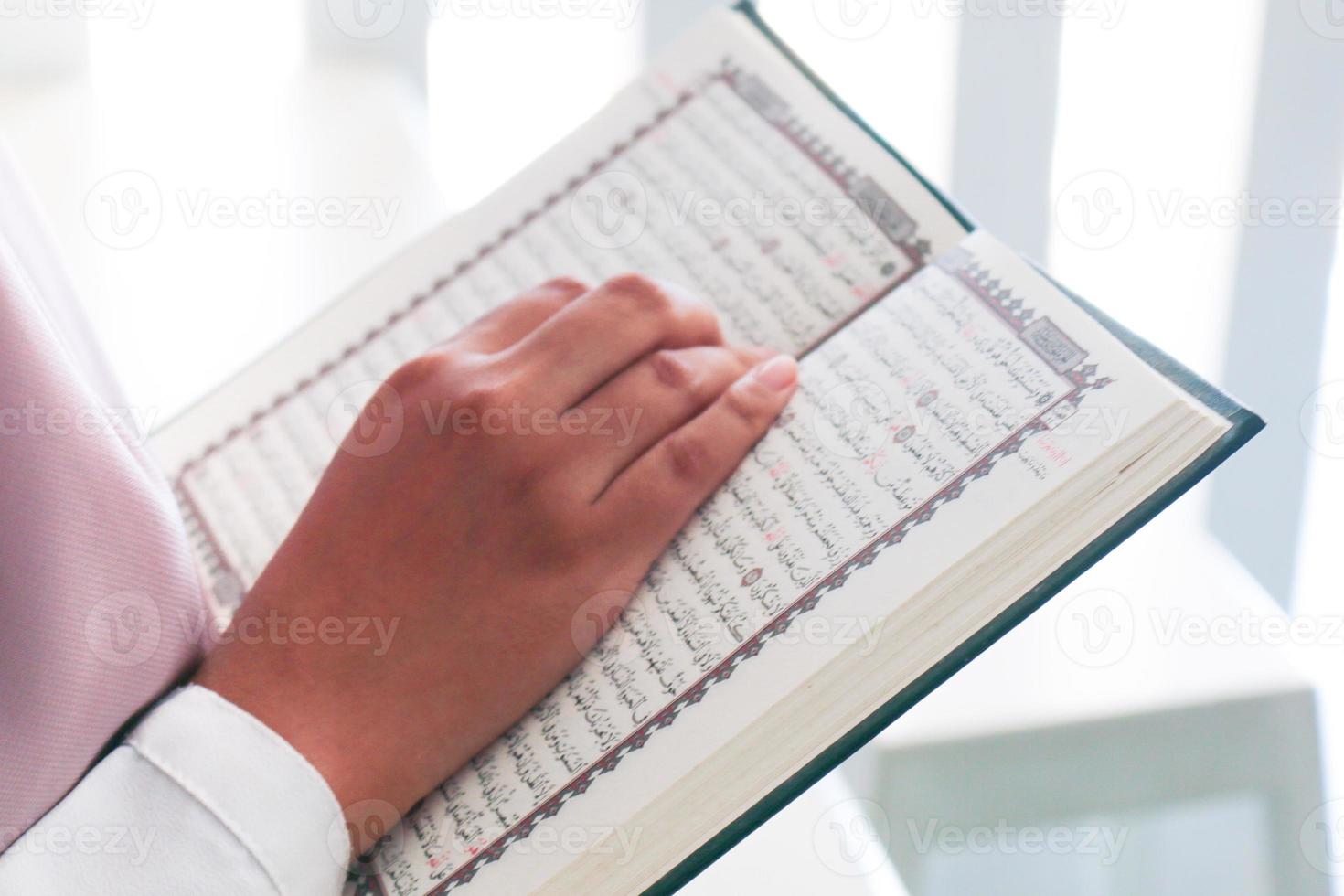 Close up of hand when reading the Holy Quran at the mosque. Selective focus photo