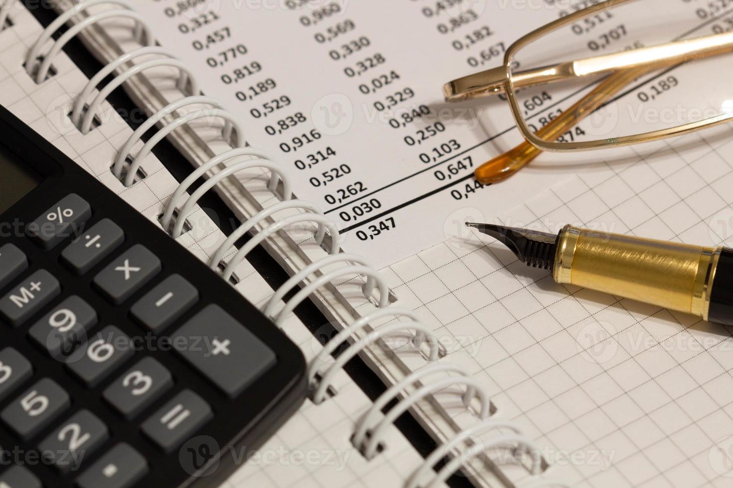 Financial report, a fountain pen, glasses and paper with numbers on the table in the office. A paper sheet full of business data. Accounts number on the data paper. Business documents. Close-up photo