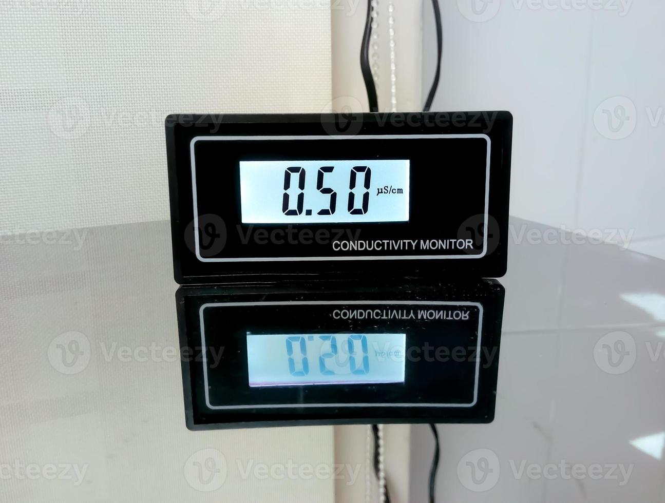 Water conductivity monitoring meter isolated and reflect on glass table, digital checker in pathology laboratory for water conductivity photo