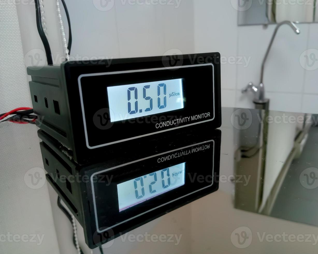 Water conductivity monitoring meter isolated and reflect on glass table, digital checker in pathology laboratory for water conductivity photo
