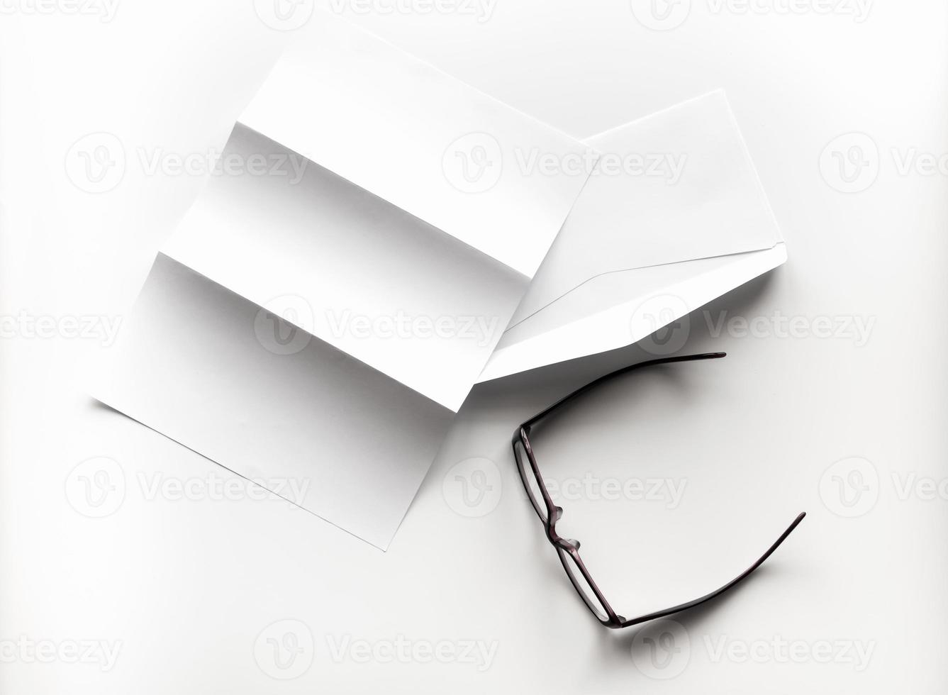 blank of letter paper and envelope with eyeglasses and pen photo